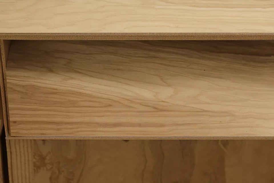 Close-up of cabinet-grade plywood edges and a tape measure on a workbench.